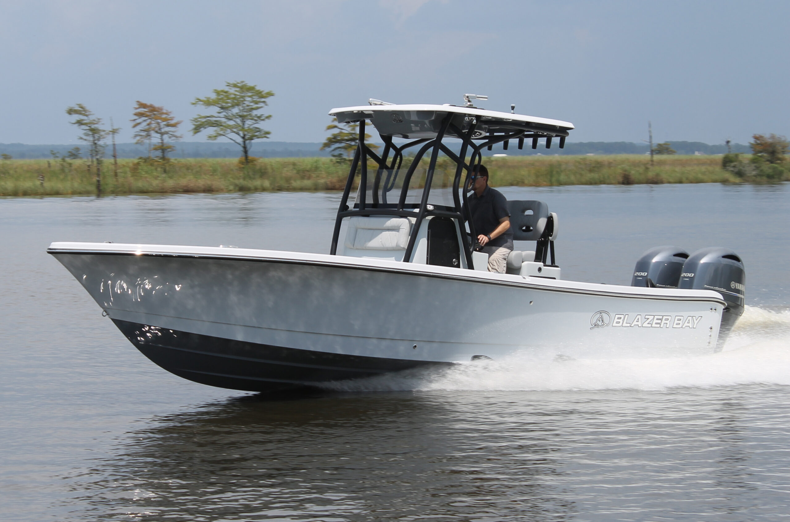 Inshore offshore hybrid boat fishing in shallow bay water near coastline